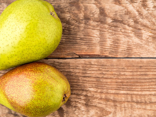 Two large juicy pears, green and red-green, on aged wooden table, top view with empty space