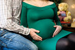 © Nestyda - Beautiful pregnant couple in love on the background of a Christmas tree, having a rest on Christmas holidays before the new year. Big pregnant belly