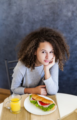 Curly hair teen girl having breakfast at home