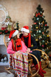 © Nestyda - Beautiful pregnant couple in love on the background of a Christmas tree, having a rest on Christmas holidays before the new year. Big pregnant belly