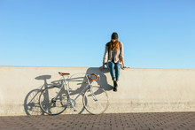 Woman Sitting Beside Her Vintage Bicycle On A Sunny Winter Day.