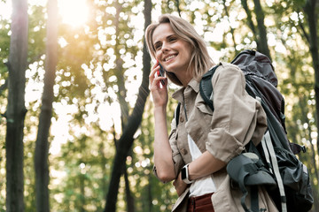 Wall Mural - Joyful young woman speaking by cellphone in forest