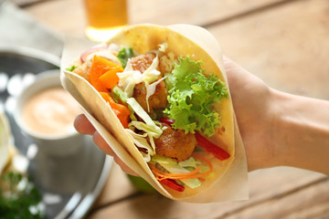 Wall Mural - Hand of woman holding delicious fish taco, closeup