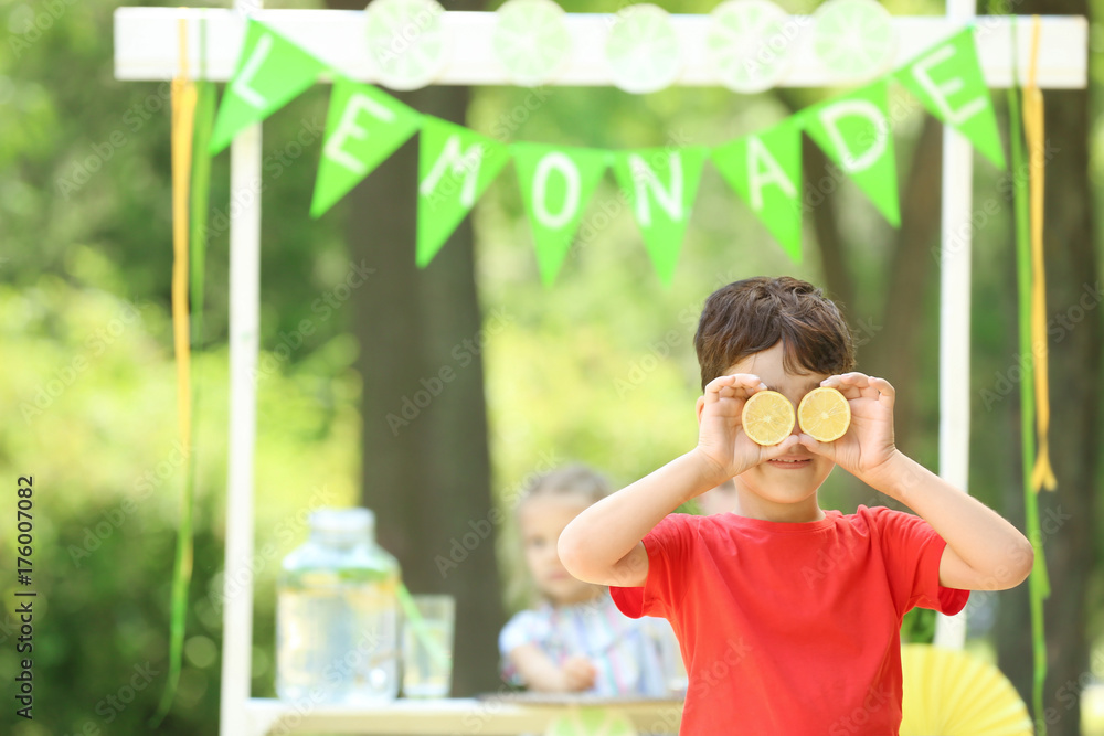 Funny little boy near lemonade stand in park