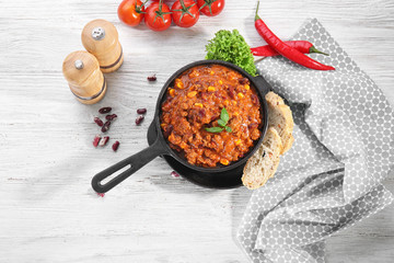 Poster - Chili con carne with fresh basil in frying pan on kitchen table