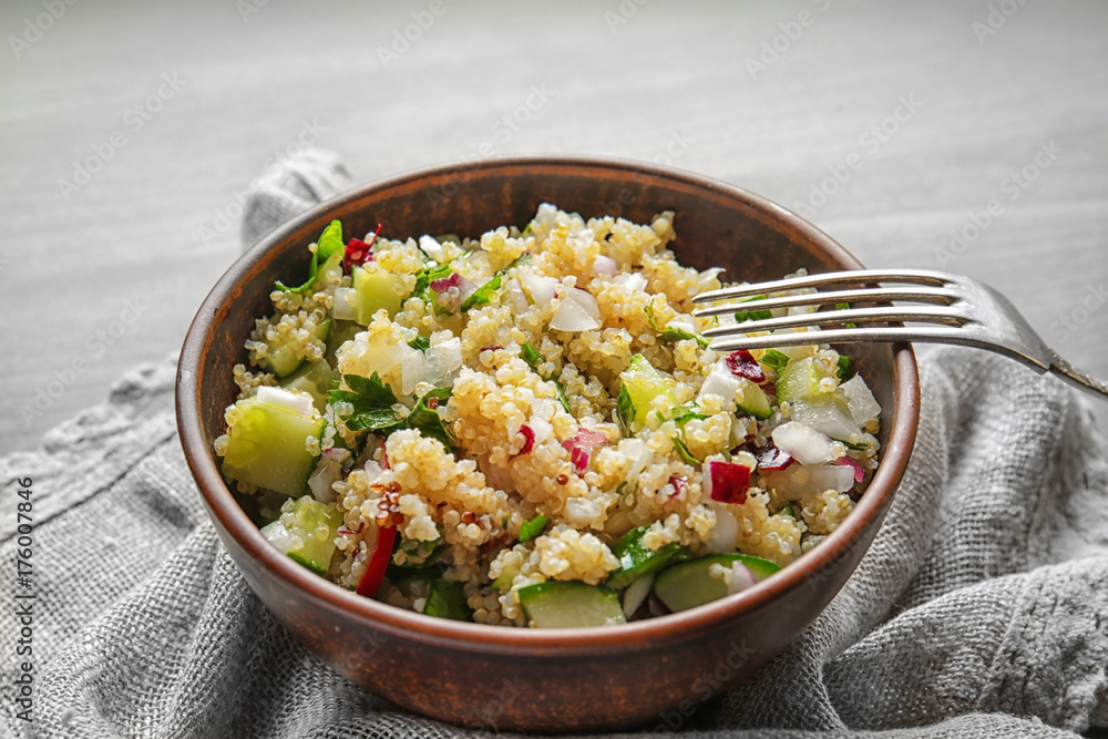 Bowl with quinoa salad on table