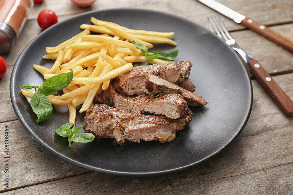 Plate with delicious grilled steak frites wooden table