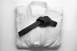 Karate uniform with black belt on white background
