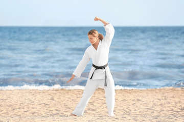 Wall Mural - Young woman practicing karate outdoors