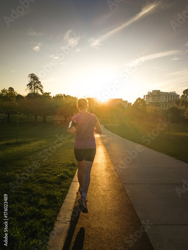 Plakat Kobieta bieg na śladzie w parku przy zmierzchem