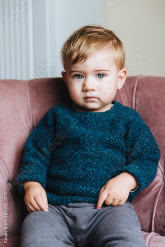 Cute Small Child With Light Hair And Blue Eyes Wears Sweater And