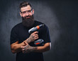 © Fxquadro - A man holds a drill over grey background.