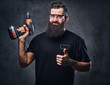 © Fxquadro - A man holds a drill over grey background.