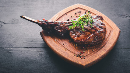 Steak on the bone. Top view. Free space for text. On a wooden background.