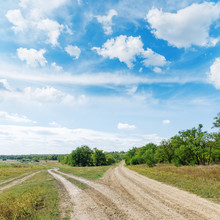 Two Roads In Green Landscape Under Blue Sky With Clouds
