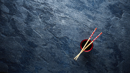 Wall Mural - Chopsticks and bowl with soy sauce on textured background