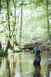 © Gonzales Photo - A patient man in waders is fly fishing on a river in forest area.
