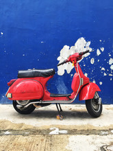 Vintage Red Scooter Against Blue Wall