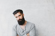 © Amir Kaljikovic Photography/Stocksy - Young man with beard leaning against a gray wall