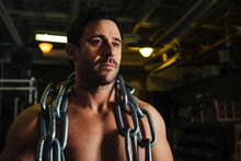 A Shirtless Muscular Male Draped In Heavy Chains.
