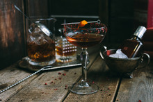 Classic Manhattan Cocktail With Orange Peel And Red Pepper Rim On Wooden Board