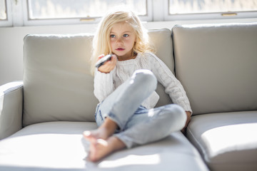 4 years old child watching tv laying down on the sofa at home alone