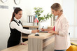 © Africa Studio - Female receptionist and woman in hotel