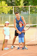 Poster - Young trainer with little children on tennis court