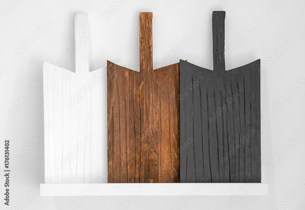 Shelf with different wooden boards on white wall