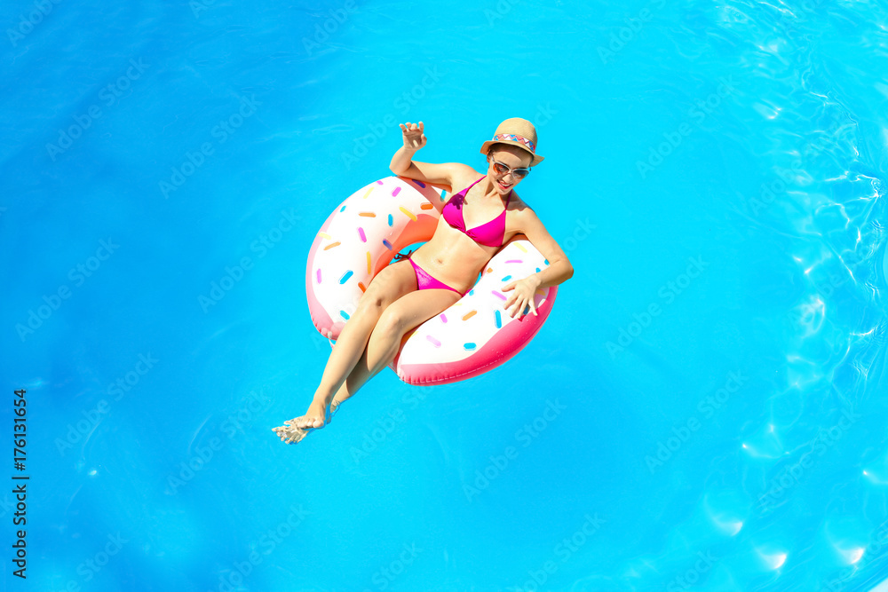Young woman relaxing on inflatable donut in swimming pool