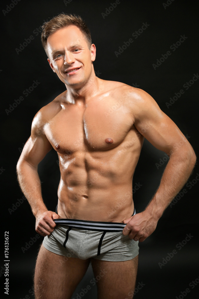 Muscular man in underwear on dark background