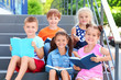 © Africa Studio - Cute little children reading books while sitting on steps outdoors