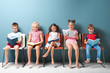 © Africa Studio - Cute little children reading books while sitting near color wall