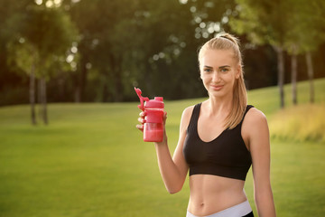 Wall Mural - Sporty young woman with protein shake outdoors