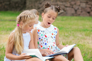 Wall Mural - Cute little girls reading books in park