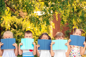 Cute little children reading books in park