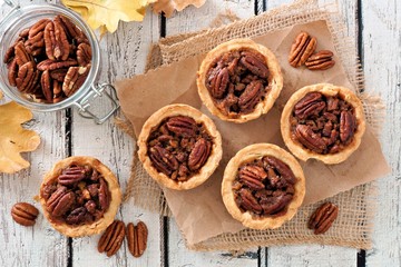 Wall Mural - Mini pecan pie tarts, above view table scene on a rustic white wood background