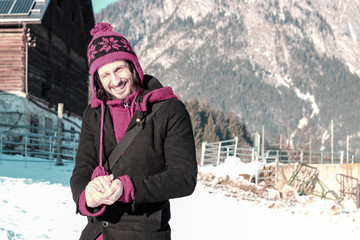 Wall Mural - young man forming a snowball in winterscape