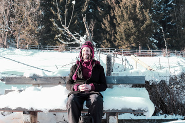 Wall Mural - young man sitting on a snowed in bench in winterscape