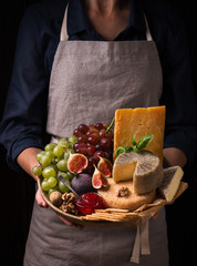 Wall Mural - Woman holding a cheese plate with fruits and jam