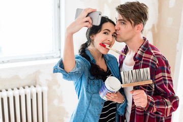 Young couple in love making a funny selfie while working together to the interior renovation of their new home