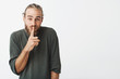 © Cookie Studio - Funny handsome bearded man making hush hand gesture asking little kid to keep silence and don't tell mom about their secret.