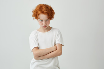 Wall Mural - Isolated portrait of unhappy little kid with red curly hair and freckles being offended by teacher that gave bad mark for his answer.