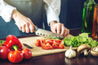 © Artem - The chef in black apron cuts vegetables. Concept of eco-friendly products for cooking