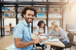 © Cookie Studio - Close up portrait of good-looking black-skinned university student sitting on meeting with friends after study, talking about group project, looking through websites on digital tablet.