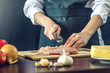 © Artem - The chef in black apron cuts chicken fillet knife. Concept of eco-friendly products for cooking