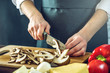 © Artem - The chef in black apron cuts mushrooms with a knife. Concept of eco-friendly products for cooking