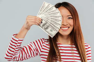 Wall Mural - Smiling asian woman in sweater is covering in money