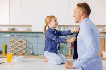 Wall Mural - Happy nice girl helping her father to get dressed