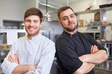 happy smiling chef and cook at restaurant kitchen